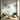 Lush mural wallpaper with leafy trees, flowers, butterflies and bird brightens a sunlit room with green chairs and natural wood decor.