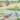 A serene rural scene with a lotus pond, wooden boat, lush greenery, elephant riders, and villagers walking by green fields and hills.