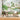 Whimsical mural wallpaper with vibrant trees, flowers, birds and a lake sets a playful scene behind a round dining table and chairs.