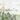 Watercolor blue bird on lush green with yellow butterflies, pink and white florals, leafy plants, pale mountains and trees backdrop.