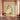 Bright, airy room with a vibrant peacock mural on the wall, pale wood bench, tall leafy vase, brown leather chair and tiled floor.