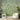 White armchair in a cozy room with pendant lighting, leafy plants, and a green wallpaper mural of birds on flowering branches.