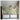 Indoor wall mural showcases a vibrant garden scene with leafy trees, colorful blossoms, white fences, fountains, and deer amid serene greenery.