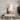 Geometric black-and-white floor pattern with a pink console, abstract art, gold sconces, and vases in an elegant modern entryway.