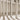 Vertical stone columns cast elongated shadows on sunlit patterned tiles, with subtle Arabic lettering adding cultural detail to the mural design.