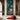Wallpaper mural featuring two cows by a lotus-filled pond, framed by arches in a minimalist room with a red cloth on a stone.