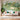 White sofa with green and pink pillows faces a gold coffee table, set against vibrant jungle wallpaper featuring trees, animals, and water.