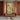 A vibrant Indian mural wallpaper with pastoral and mythological motifs fills an alcove above a low console with pottery and decor.
