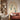 Contemporary room with a rust sofa, patterned cushions, white chair, desk, shelves, and peacock wallpaper on a feature wall.