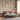Elegant floral wallpaper with delicate birds behind a wooden bed, green bedding, busts, and sheer rust curtains in a bright room.