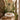 Palm leaf mural in soothing greens enhances a bright sunroom with glass windows, a round cushioned chair, tropical plants and woven rug.