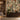 Leaf-patterned wallpaper in warm earthy hues, styled with a modern sideboard, leafy plant, books, and bowl in sunlit living space.
