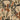 Earthy green, brown, orange, and beige stylized leaves and flowers form a vintage-inspired pattern on a textured wallpaper background.