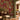 Deep red wallpaper with a tropical pattern of palm trees and peacocks, set behind a dark wood console table and an upholstered bench.