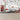 Cityscape wall mural in a child‚Äôs room, with colorful roads, cars, buildings and playful transportation motifs above a red race car bed.