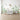 Botanical wall mural with delicate flowers, ferns, butterflies, and bees sets a serene backdrop in a nursery with white crib and dresser.