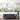 Botanical mural wallpaper with leafy branches, delicate flowers, and hummingbirds on a white wall behind a velvet gray sofa.