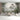 Tropical wall mural with lush green foliage and distant wildlife, paired with light gray sofas and a round wooden coffee table in a minimalist living room.