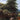 Elegant horses graze beneath tall, leafy trees on a lush green pasture, with sunlit hills and distant rooftops adding depth to the mural‚Äôs tranquil scene.