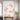 Floral wallpaper with pink lotus blooms and green leaves sets off a red cushioned bench, potted plant, and tall arched window.