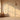 A softly lit room with floral-patterned beige wallpaper, wooden floor, arched window, wicker jug, white vase and elegant pendant lamp.